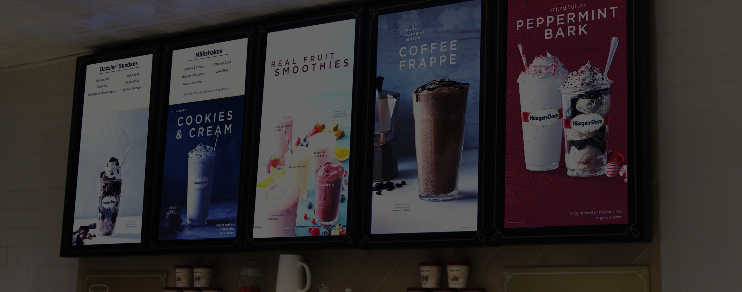 Five vertical digital menu boards displaying a restaurant's coffee, ice cream, and smoothie offerings.							