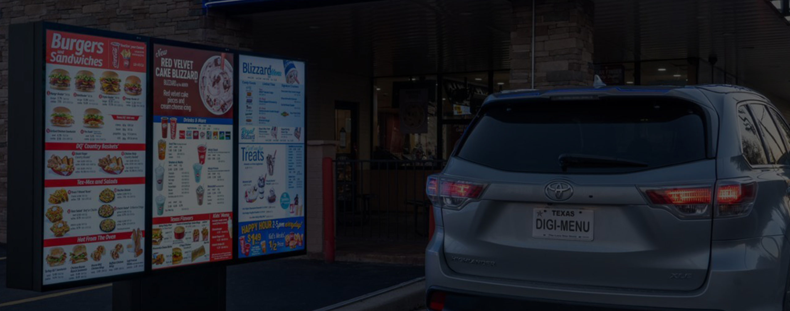 A Toyota SUV is driving past a digital Dairy Queen drive-thru menu board.							